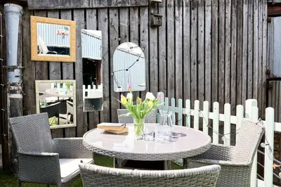 a table with chairs and flowers on a patio at Llysfaen Cottage in Brecon