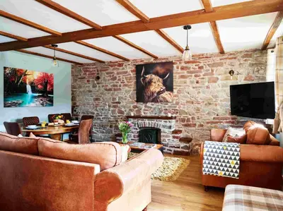 a living room with couches and a stone fireplace at Llysfaen Cottage in Brecon