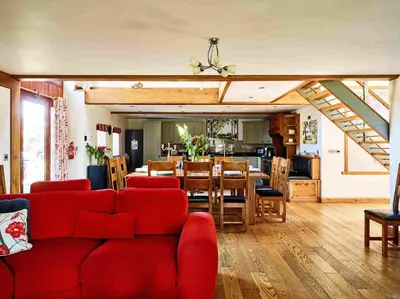 a living room with a red couch and a dining room at Oak Barn in Brecon