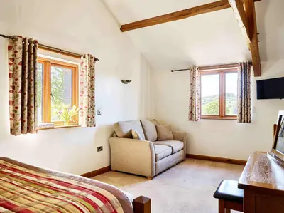 a living room with a couch and two windows at Oak Barn in Brecon