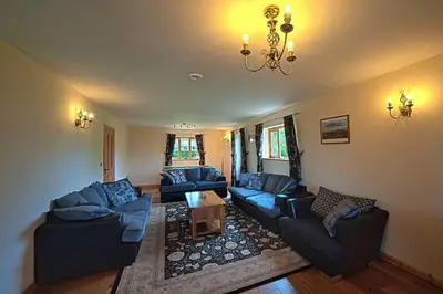a living room with blue couches and a chandelier at Poplar Tree Eco Lodge in Brecon