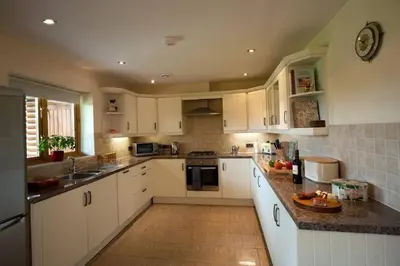 a kitchen with white cabinets and granite counter tops at Poplar Tree Eco Lodge in Brecon