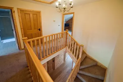 a wooden staircase in a house with a chandelier at Beech Tree Eco Lodge in Brecon