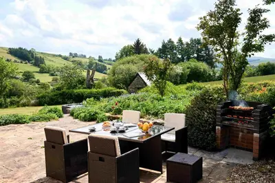 a patio with a table and chairs and a fire place at Onnen Fawr Farmhouse in Brecon