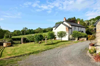 a dirt road in front of a white house at Onnen Fawr Farmhouse in Brecon