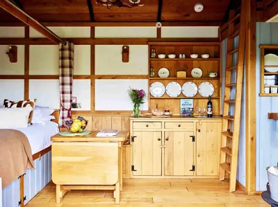 a kitchen with wooden cabinets and a bed in a room at The Flying Scotsman Shepherd's Hut with Hot Tub in Brecon