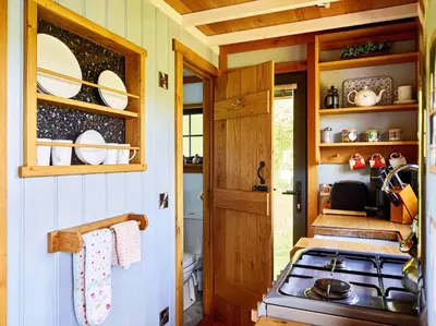 a kitchen with a stove and a wooden door at The Flying Scotsman Shepherd's Hut with Hot Tub in Brecon