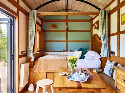 a bedroom with a bed and a table with flowers at The Orient Express Shepherd's Hut with Hot Tub in Brecon