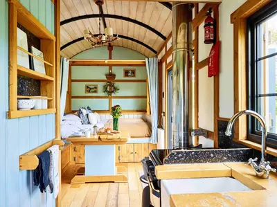 a kitchen with a sink and a room with a bed at The Mallard Shepherd's Hut with Hot Tub in Brecon