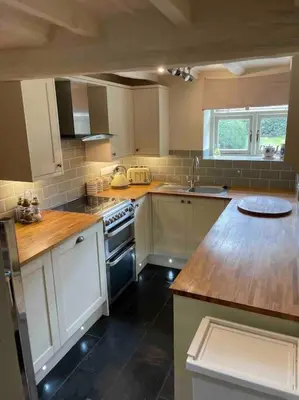 a kitchen with white cabinets and a wooden counter top at Ty Twty, Montgomery Cottage in Montgomery