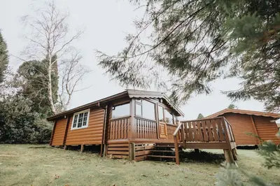 a large wooden cabin with a large deck at Rustic Log Cabin in Snowdonia - 2 Bedrooms & Parking in Ffestiniog