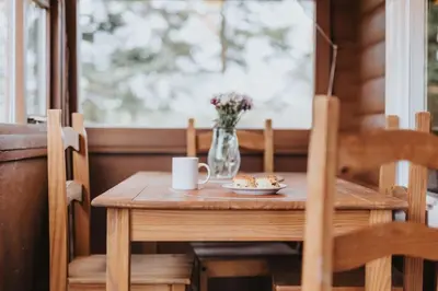 a wooden table with a vase of flowers and a plate of food at Rustic Log Cabin in Snowdonia - 2 Bedrooms & Parking in Ffestiniog