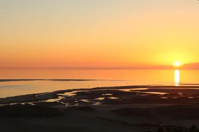 a sunset over the ocean with the sun setting at Beach Vista Apartment Three in Barmouth in Barmouth