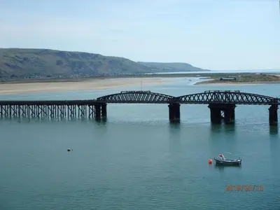 a bridge over a river with a boat in the water at Beach Vista Apartment Three in Barmouth in Barmouth