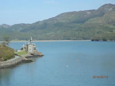 a building in the middle of a lake with mountains at Beach Vista Apartment Three in Barmouth in Barmouth