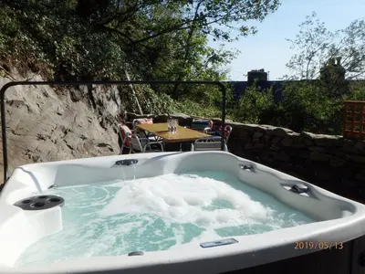 a bath tub with water in it with a table and a table at Bryn Mair in Barmouth in Barmouth