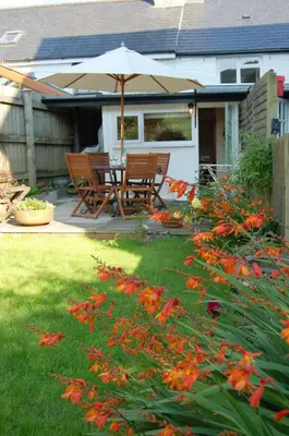 a patio with a table and chairs under an umbrella at Bronhaul Cottage in Pennal in Pennal