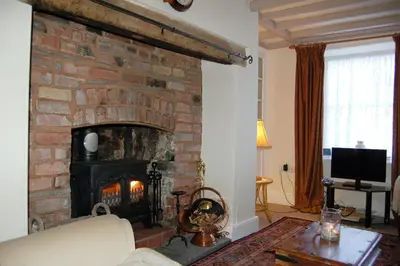 a living room with a brick fireplace and a couch at Bronhaul Cottage in Pennal in Pennal