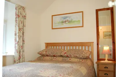 a bedroom with a bed and a lamp and a mirror at Bronhaul Cottage in Pennal in Pennal