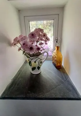 a vase with flowers sitting on a table next to a window at Cae Tudur Remote Rural Cottage near Barmouth in Barmouth