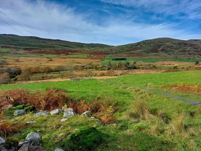 a grassy field with hills in the background at Cae Tudur Remote Rural Cottage near Barmouth in Barmouth