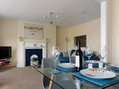a living room with a glass table with wine glasses at Hafan Y Traeth Beach Front Apartment in Barmouth in Barmouth