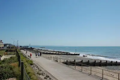 people walking on the beach near the ocean at Chwerthin Y Mor Beach House in Tywyn