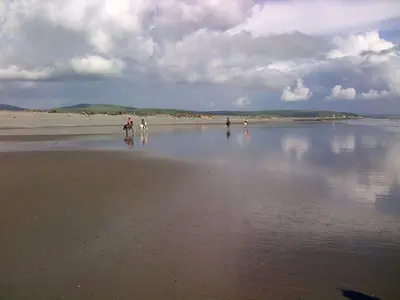 a group of people walking on the beach at Chwerthin Y Mor Beach House in Tywyn