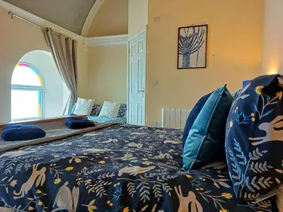 a bedroom with a bed with a blue blanket at Ty Capel in Tywyn in Tywyn