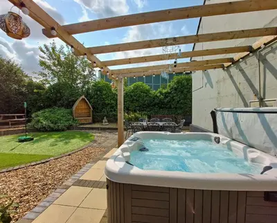 a hot tub in a backyard with a wooden pergola at Ty Capel in Tywyn in Tywyn