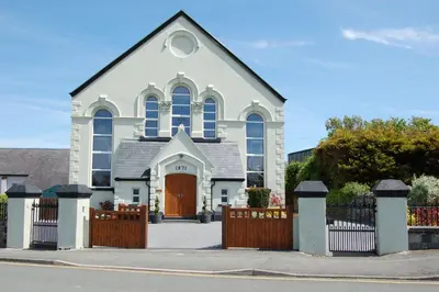 a white church with a wooden fence in front of it at Ty Capel in Tywyn in Tywyn