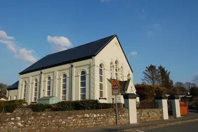 a white church with a black roof on a street at Ty Capel in Tywyn in Tywyn