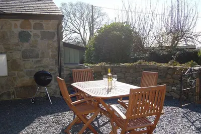 a wooden table with four chairs and a grill at Anneddle Cottage in Talybont, near Barmouth in Talybont