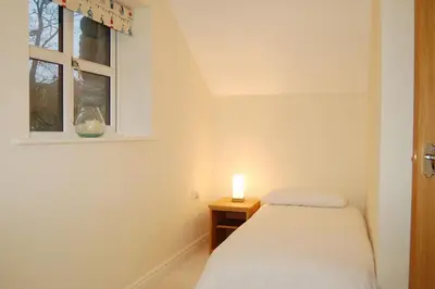 a small bedroom with a bed and a candle on a table at Anneddle Cottage in Talybont, near Barmouth in Talybont