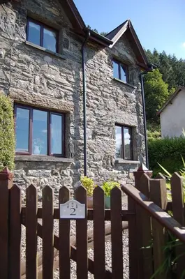 a wooden fence in front of a stone house at Tre-Allt Gorgeous Cottage in Dolgellau