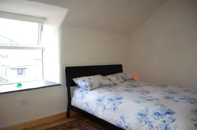 a bedroom with a bed and a window at Y Bwthyn Bach Cute Stone Cottage in Tywyn in Tywyn