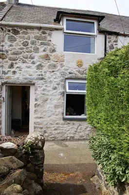 a stone house with two windows and a door at Y Bwthyn Bach Cute Stone Cottage in Tywyn in Tywyn