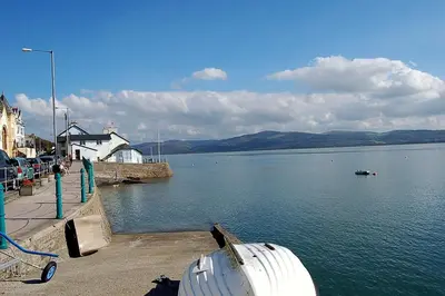 a boat is docked on the shore of a lake at Y Bwthyn Bach Cute Stone Cottage in Tywyn in Tywyn