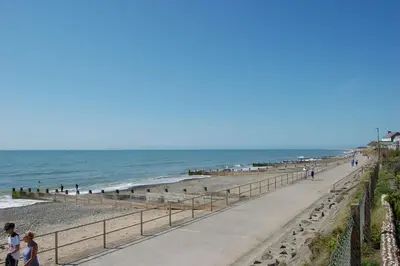 people walking on the beach near the ocean at Ty Traeth Beach House in Tywyn