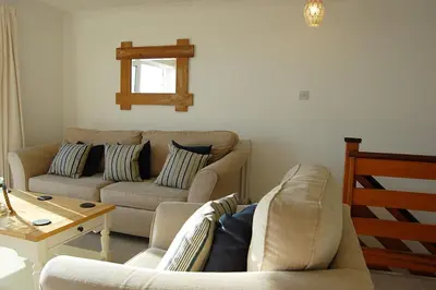 a living room with two couches and a table at Ty Traeth Beach House in Tywyn