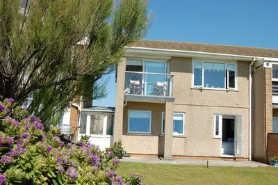 a house with two chairs on a balcony at Tywyn Beach House in Tywyn