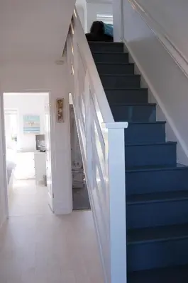 a hallway with blue stairs in a house at Tywyn Beach House in Tywyn