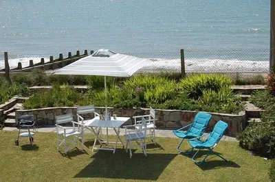 a table and chairs with an umbrella and the beach at Tywyn Beach House in Tywyn