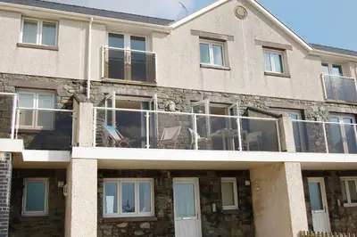 a large brick building with a balcony with windows at Sunset Bay Beach House in Tywyn in Tywyn