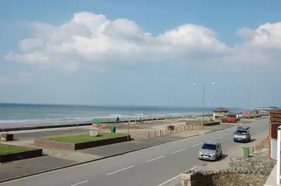 a highway with cars driving down a road next to the beach at Sunset Bay Beach House in Tywyn in Tywyn