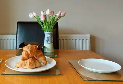a table with a plate of croissants and a vase of flowers at Swn Y Tonnau in Tywyn