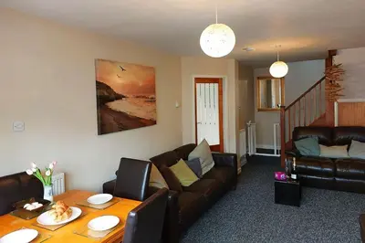 a living room with a couch and a table at Swn Y Tonnau in Tywyn