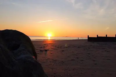 a sunset on the beach with the sun setting at Swn Y Tonnau in Tywyn