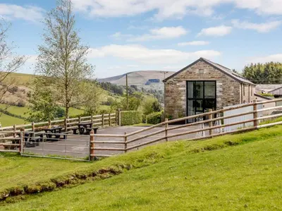 a barn conversion with a wooden fence and green grass at 2 Bed in Brecon oc-bn100 in Cray