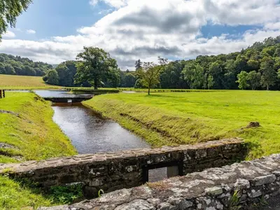 a stone bridge over a river in a field at 4 Bed in Bala oc-75288 in Llandderfel